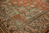 Textured vintage Heriz rug with geometric floral motifs, showcasing rust, dusty blue, and worn pile.