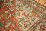 Distressed vintage Heriz carpet, geometric floral pattern in dusty terra cotta, pale blue, and faint foundation.