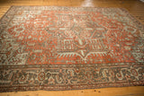Distressed vintage Heriz carpet border showing geometric floral motifs in rust, slate, and oxidized blue.