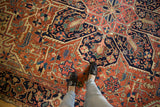 Antique Heriz carpet's geometric vinery and floral cross-sections in brick red and navy.