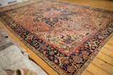 Antique Heriz carpet's dramatic medallion and geometric vinery in navy, brick red.