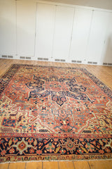 Antique Heriz carpet border and field with navy blue, brick red, geometric vinery, floral motifs, and even wear.