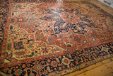 Intricate navy border with red and yellow geometric-floral patterns on an antique Heriz rug.