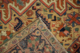 Hand-knotted Heriz rug, folded corner revealing geometric vinery in brick red, navy, saffron.