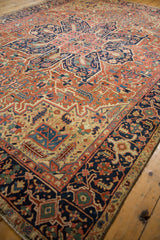 Antique Heriz rug corner with navy border, geometric vinery, and floral motifs in brick red.
