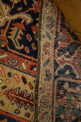 Antique Heriz carpet: hand-knotted pile with navy, brick red, saffron patterns, and woven foundation.