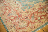 Distressed Oushak carpet corner with blush coral field, teal border, and subtle abrashes.