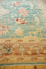 Distressed Oushak rug in aqua blue with blush coral border and even knot wear.