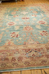 Distressed Oushak carpet showing sky blue field, blush coral, and wine red floral motifs.