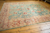 Distressed Oushak rug corner with blush coral border and faded aqua field, showing wear.