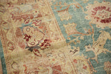 Distressed Oushak carpet showing abrashes, antique ivory, aqua blue, and coral floral design.