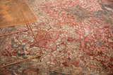 Distressed vintage Persian Heriz rug showcasing geometric vinery and palmettes in rich red, blue, ivory tones.
