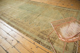 Distressed vintage Malayer carpet, worn pile texture, muted blue and beige field, vine borders.