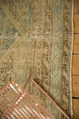 Distressed Malayer carpet texture revealing faint foundation, soft beige, and faded blue motifs.
