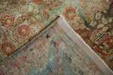 Corner of distressed Sarouk rug revealing worn floral pile and hand-knotted weave.