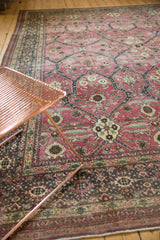 Distressed raspberry Tabriz carpet with asymmetric floral lattice and visible foundation wear.