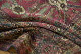 Folded distressed Tabriz carpet showing worn raspberry red and navy floral palmette patterns.