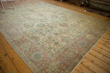 Angled view of a distressed Tabriz carpet with an ivory field, slate blue details, and dusty rose border.