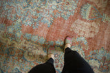 Distressed vintage Mahal carpet displaying Rococo floral motifs in brick, powder blue, and ivory.