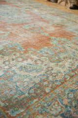 Distressed texture of a vintage Mahal carpet with muted brick, blue, and ivory floral patterns.