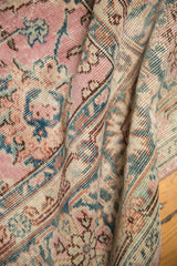 Distressed pink, indigo, and ivory palmette motifs on a folded vintage Sparta carpet.