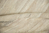 Folds of the New Kilim carpet showcasing abrashed hand-woven texture in natural wool tones.