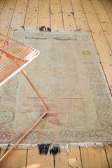 Worn pile of a distressed Oushak rug with light tatter and blush, gold floral border.