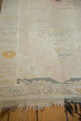 Distressed vintage Oushak rug's light tatter, abrashed blush field, and gold border.