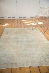 Distressed vintage Oushak rug in beige, apricot, blue, featuring faded medallion and spandrels.