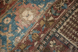 Distressed Bakhtiari carpet close-up, revealing worn pile, tree-of-life motif, and exposed foundation.
