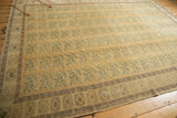 Pale dusty gold field, ocean blue green florals, and coffee brown meandering border of a vintage Oushak.