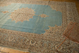 Angled view of a distressed Tabriz carpet's ivory medallion on an abrashed watery blue field.