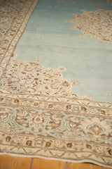 Angled view of a vintage Tabriz carpet's even wear, with ivory motifs on a watery blue field.