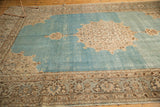 Angled view of a distressed Tabriz carpet showing the ivory medallion on a watery, abrashed blue field.