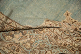 Folded vintage Tabriz carpet showing the soft, distressed texture of its aqua blue pile and brown border.