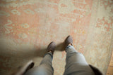 Distressed vintage Oushak rug surface with pale peach, ivory, and silver tones showing wear.