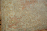 Distressed Oushak carpet showing faded pale peach and ivory motifs on the edge.