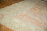 Distressed vintage Oushak rug texture with visible wear, showing pale peach and ivory patterns.