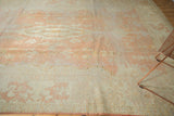 Distressed vintage Oushak rug with faded pale peach and ivory tones, showing wear.