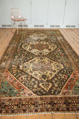 Distressed Bakhtiari rug runner corner with terracotta, teal, and beige borders, showing fringe and pile wear.