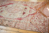 Faded cherry red floral medallion and distressed ivory pile of a vintage Oushak rug.