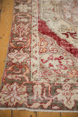 Distressed pile of vintage Oushak rug, showing faded red, beige, and saffron floral motifs.
