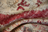 Distressed vintage Oushak rug showing cherry red and beige patterns with visible knot heads.