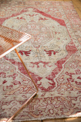 Textured pile of vintage distressed Oushak rug, faded cherry red and beige floral patterns.