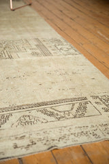 Distressed Oushak rug texture with ivory field and geometric chocolate brown motifs.