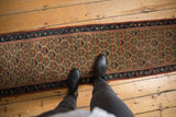 Antique Caucasian runner, a repeating geometric plant motif in saffron, madder red, and navy.
