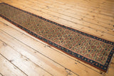 Close-up of antique Caucasian runner's germinating plant motifs with madder, saffron, and oxidized green.