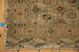 Distressed corner of a vintage Turkmen runner, with sand, terra cotta, and navy geometric patterns.
