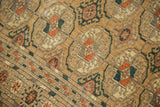 Close-up of distressed Turkmen runner's floral gul motifs with visible, even wear.
