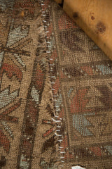 Folded vintage Belouch rug showing camel hair pile, geometric foundation weave, and white stitched secured edge.